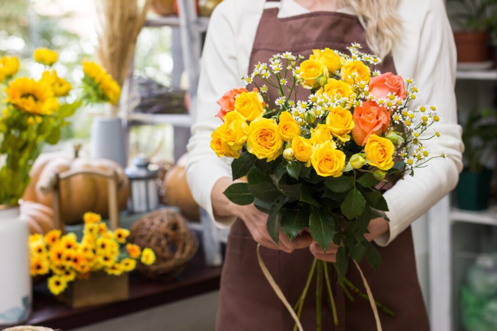 Florist holding a yellow and orange rose bouquet.