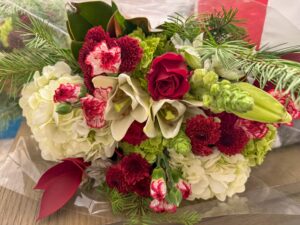 Mixed bouquet with red roses, white lilies, hydrangeas, and greenery.